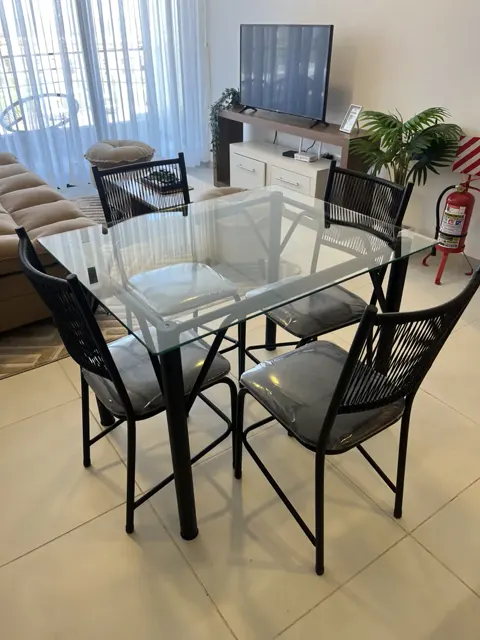 Comedor con mesa de vidrio y TV